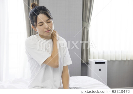 A young woman with stiff shoulders after waking up A young woman with stiff shoulders after waking up 92810473