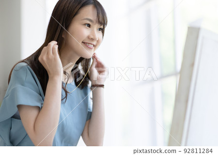 A woman getting dressed in front of a mirror 92811284