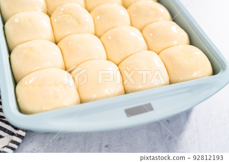 Brushing dinner rolls with mixture of egg and milk before baking in the baking pan. 92812193