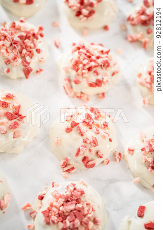 Dipping chocolate cookies into the melted white chocolate to prepare peppermint white chocolate cookies. 92812194