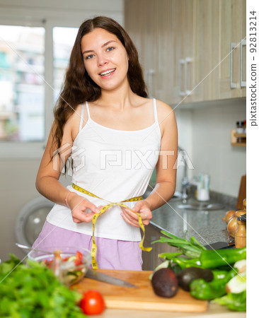 Young pretty girl measuring her waist with measuring tape Young pretty girl measuring her waist with measuring tape 92813214