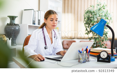 Young woman doctor is working at a computer in the office Young woman doctor is working at a computer in the office 92813349