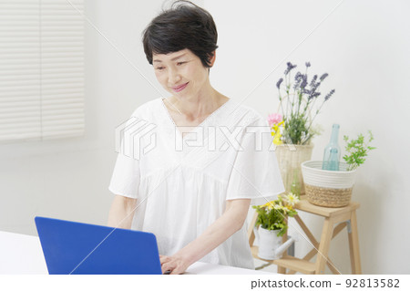Senior woman using a laptop in the living room 92813582