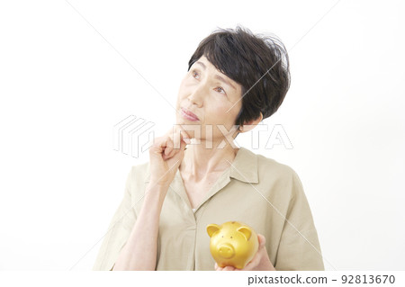 拿著存錢罐白色背景的高級女性思考 92813670