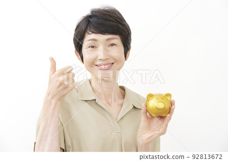 拿著存錢罐和打手勢好的白色背景的資深婦女 92813672