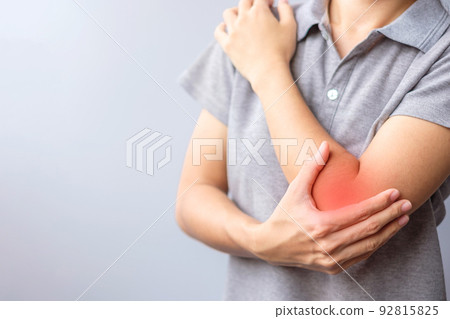 adult female with her muscle pain on gray background. Woman having elbow ache due to lateral epicondylitis or tennis elbow. injuries and medical concept 92815825