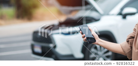 woman driver using mobile phone during problem car. Breakdown or broken car on road. Vehicle Insurance, maintenance and service concept 92816322