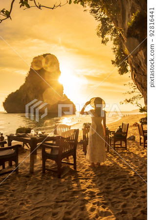 Woman tourist in white dress dinner in restaurant cave on Phra nang Beach at sunset, Railay, Krabi, Thailand. vacation, travel, summer, Wanderlust and holiday concept 92816441