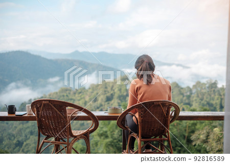 Happy woman drinking coffee and eating breakfast against mountain view at countryside home or homestay in the morning. Vacation, blogger, SoloTravel, journey, trip and relaxing concept Happy woman drinking coffee and eating breakfast against mountain view at countryside home or homestay in the morning. Vacation, blogger, SoloTravel, journey, trip and relaxing concept 92816589