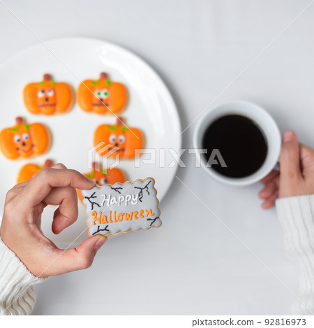 woman hand holding funny Halloween Cookie during drinking coffee. Happy Halloween day, Trick or Threat, Hello October, fall autumn, Traditional, party and holiday concept woman hand holding funny Halloween Cookie during drinking coffee. Happy Halloween day, Trick or Threat, Hello October, fall autumn, Traditional, party and holiday concept 92816973