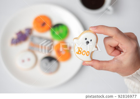 woman hand holding funny Halloween Cookie during drinking coffee. Happy Halloween day, Trick or Threat, Hello October, fall autumn, Traditional, party and holiday concept woman hand holding funny Halloween Cookie during drinking coffee. Happy Halloween day, Trick or Threat, Hello October, fall autumn, Traditional, party and holiday concept 92816977