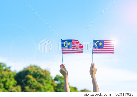 hand holding Malaysia flag on blue sky background. September Malaysia national day and August Independence day hand holding Malaysia flag on blue sky background. September Malaysia national day and August Independence day 92817023