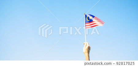 hand holding Malaysia flag on blue sky background. September Malaysia national day and August Independence day hand holding Malaysia flag on blue sky background. September Malaysia national day and August Independence day 92817025