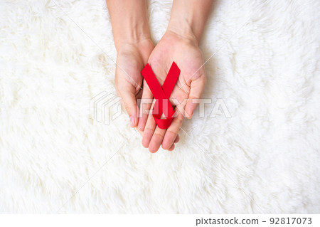 Hand holding Red Ribbon for supporting people living and illness. Healthcare and safe sex concept. December World Aids Day and multiple myeloma Cancer Awareness month Hand holding Red Ribbon for supporting people living and illness. Healthcare and safe sex concept. December World Aids Day and multiple myeloma Cancer Awareness month 92817073
