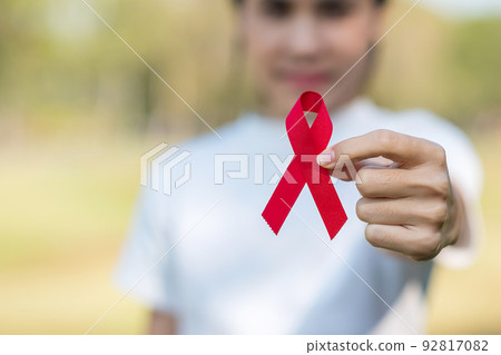 Hand holding Red Ribbon for supporting people living and illness. Healthcare and safe sex concept. December World Aids Day and multiple myeloma Cancer Awareness month Hand holding Red Ribbon for supporting people living and illness. Healthcare and safe sex concept. December World Aids Day and multiple myeloma Cancer Awareness month 92817082