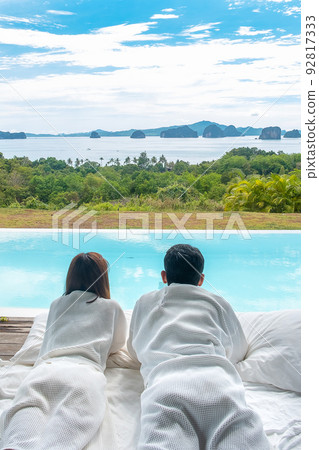 Happy Couple traveler enjoy Beautiful ocean view, Tourists relaxing in tropical luxury resort with swimming pool.Together, honeymoon, love, travel and summer vacation concept Happy Couple traveler enjoy Beautiful ocean view, Tourists relaxing in tropical luxury resort with swimming pool.Together, honeymoon, love, travel and summer vacation concept 92817333