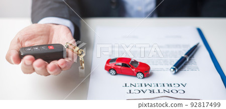 Businessman hand holding red car toy with vehicle keyless, pen and contract document. buy and sale, insurance, rental and contract agreement concepts Businessman hand holding red car toy with vehicle keyless, pen and contract document. buy and sale, insurance, rental and contract agreement concepts 92817499