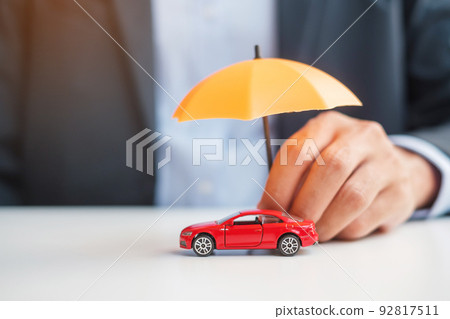 Businessman hand holding umbrella and cover red car toy on table. Car insurance, warranty, repair, Financial, banking and money concept Businessman hand holding umbrella and cover red car toy on table. Car insurance, warranty, repair, Financial, banking and money concept 92817511