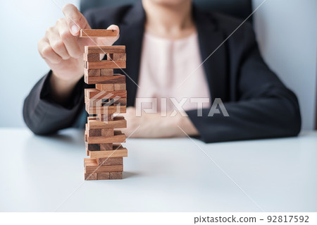 Businesswoman hand placing or pulling wooden block on the tower. Business planning, Risk Management, Solution and strategy Concepts 92817592