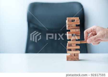 Businessman hand placing or pulling wooden block on the tower. Business planning, Risk Management, Solution and strategy Concepts 92817593