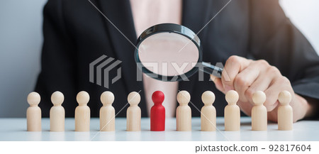 Businesswoman hand holding magnifying glass for recruiting leader man wooden from crowd of employees.Human resource management, Recruitment, Teamwork, hiring and leadership Concepts 92817604
