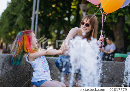 Mother and daughter having fun on girl birthday splashing near city fountain 92817779