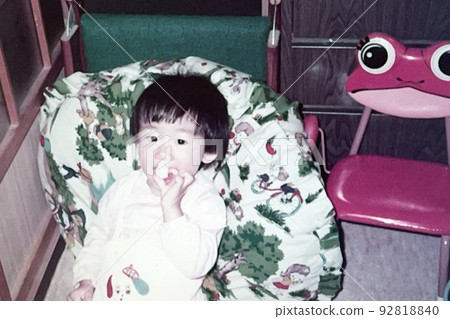Showa 50's 1-year-old girl leaning on a cushion and eating something Showa 50's 1-year-old girl leaning on a cushion and eating something 92818840