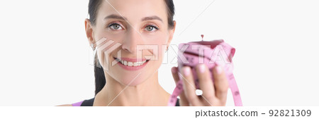 Happy sportswoman holds an apple wrapped with measuring tape Happy sportswoman holds an apple wrapped with measuring tape 92821309