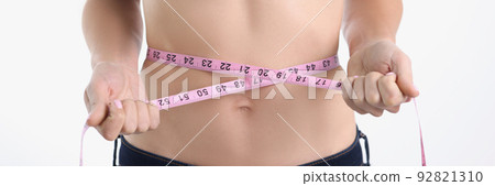 A woman measures her waist with a tape, blurry 92821310
