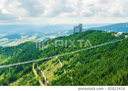 Aerial view of the worlds longest 721 meter suspension footbridge Sky bridge and observation tower the Sky walk in the forest, between mountains, Dolni Morava Ski Resort, Czech Republic.  92821418