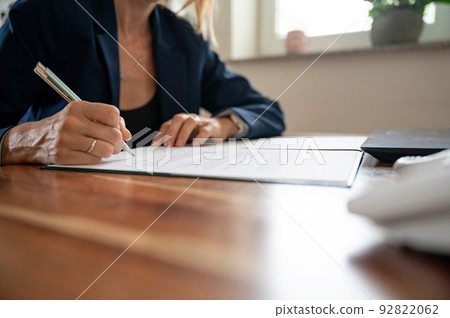 Businesswoman sitting at her office desk signing a contract 92822062