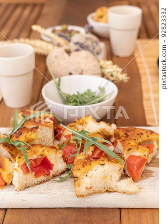 Tipical summer south Italian appetizer focaccia with cherry tomatoes and rucola served outdoor 92823332