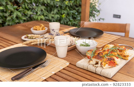 Tipical summer south Italian appetizer focaccia with cherry tomatoes and rucola served outdoor Tipical summer south Italian appetizer focaccia with cherry tomatoes and rucola served outdoor 92823333