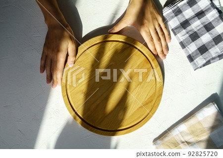 Man hand holding empty round wooden pizza board in hand, white background. Mockup 92825720