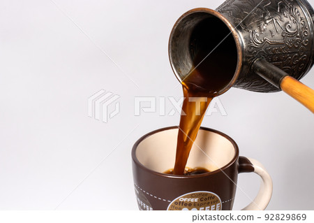 Black coffee in the morning. The process of pouring espresso, americano from copper turk into a coffee cup. Black coffee in the morning. The process of pouring espresso, americano from copper turk into a coffee cup. 92829869