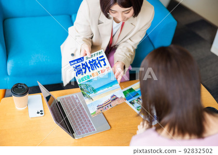 A woman making plans while looking at an overseas travel brochure 92832502