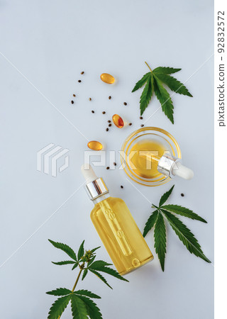 CBD oil in bottle with pipette, capsules, marijuana leaves on white background CBD oil in bottle with pipette, capsules, marijuana leaves on white background 92832572
