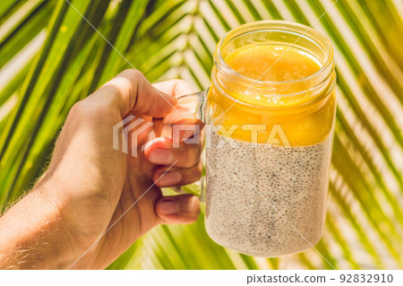 Chia seed pudding with almond milk and fresh mango topping in hand Chia seed pudding with almond milk and fresh mango topping in hand 92832910