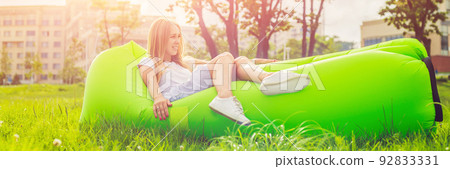 Young woman resting on an air sofa in the park. BANNER, long format Young woman resting on an air sofa in the park. BANNER, long format 92833331