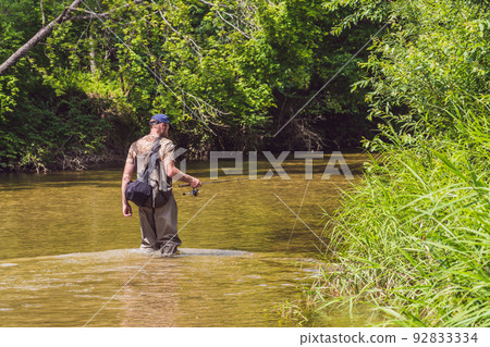 Man fishing on a mountain river with a ultralight spinning using fishing wobblers. He got his hook hooked for something 92833334
