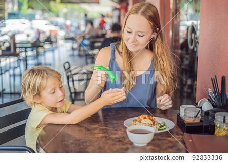 Mother and son using wash hand sanitizer gel in a cafe before eating Mother and son using wash hand sanitizer gel in a cafe before eating 92833336