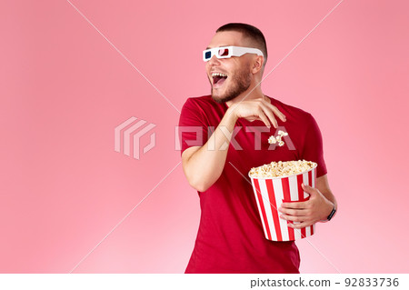 Young caucasian man in 3d glasses eating popcorn 92833736