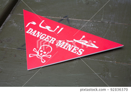Arabic/English minefield warning red sign - Danger Mines. White skull-and-crossbones on a red. Arabic/English minefield warning red sign - Danger Mines. White skull-and-crossbones on a red. 92836370