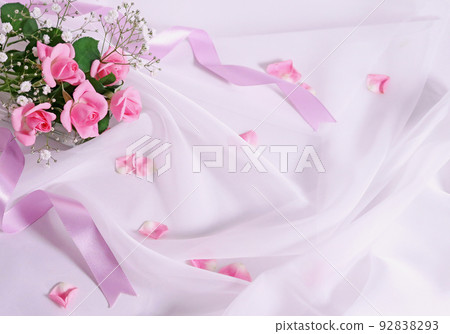 Pink roses and mistletoe bouquet and ribbon on white fabric drape Pink roses and mistletoe bouquet and ribbon on white fabric drape 92838293