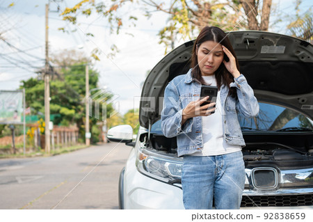 Angry Asian woman and using mobile phone calling for assistance after a car breakdown on street. Concept of vehicle engine problem or accident and emergency help from Professional mechanic Angry Asian woman and using mobile phone calling for assistance after a car breakdown on street. Concept of vehicle engine problem or accident and emergency help from Professional mechanic 92838659