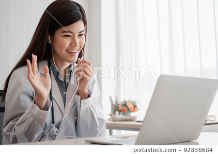 Asian woman doctor is online visiting with a patient on the internet application and Listening of the symptoms and explains how to treat the initial disease, Concept of Medical technology. 92838684