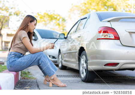 Woman drivers call insurance after a car accident before taking pictures and sending insurance. Online car accident insurance claim idea after submitting photos and evidence to an insurance company. Woman drivers call insurance after a car accident before taking pictures and sending insurance. Online car accident insurance claim idea after submitting photos and evidence to an insurance company. 92838858