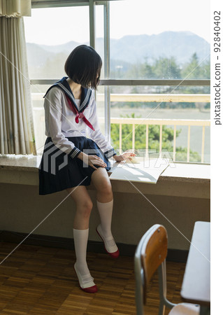 一個高中女生在教室的窗邊看筆記本 92840402