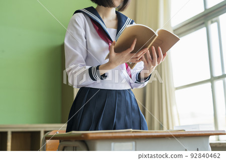 High school girl reading a classroom textbook 92840462