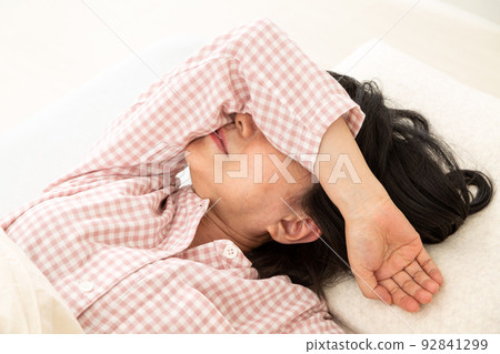 A middle-aged woman in pajamas who can't sleep in her bedroom 92841299